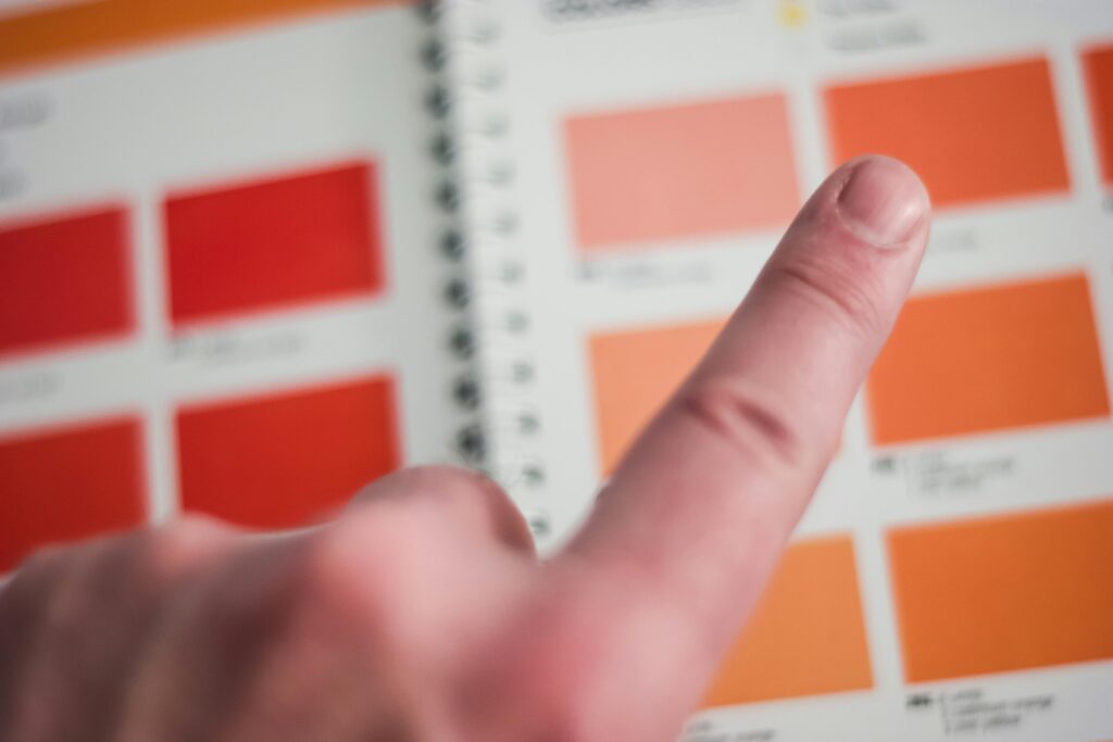 A finger points at a color swatch on a vibrant palette inside an office environment.