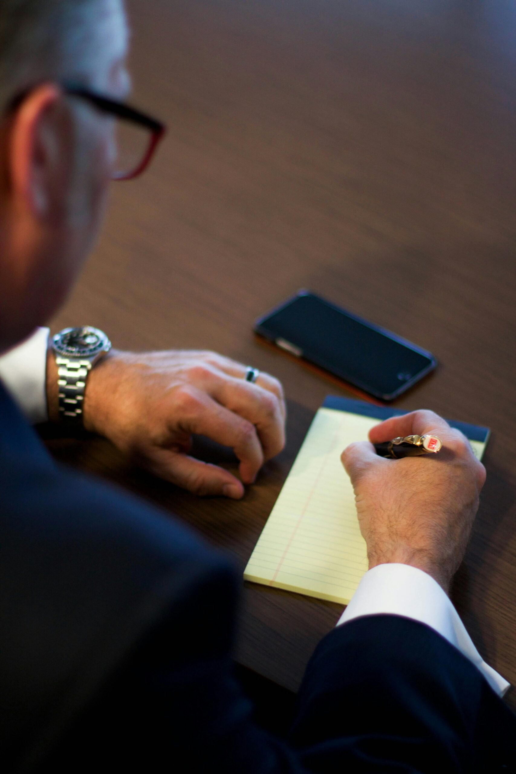 Close-up of a businessman writing notes in an office, showcasing a professional work environment.