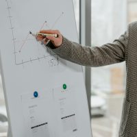 Close-up of a business professional presenting data with a graph on a whiteboard indoors.